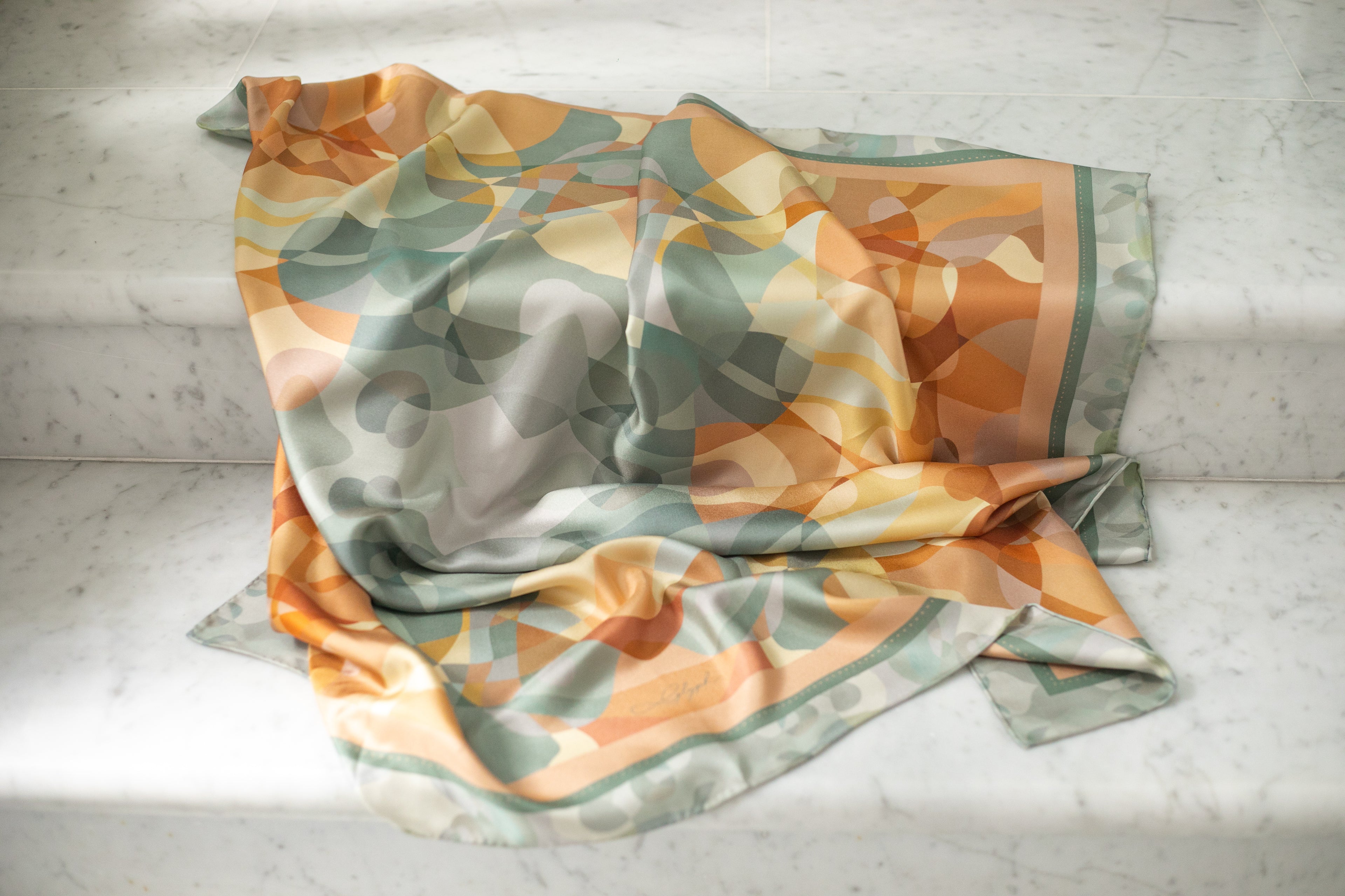 Harmony silk scarf by Glyph draped on marble, highlighting the soft texture, natural sheen and fluidity of the silk twill.