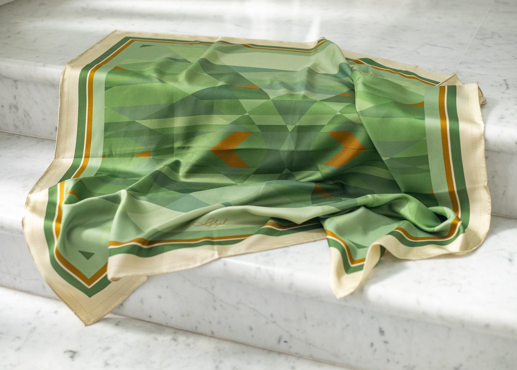 Silent Compass silk scarf by Glyph draped on marble, highlighting the soft texture, natural sheen and fluidity of the silk twill.