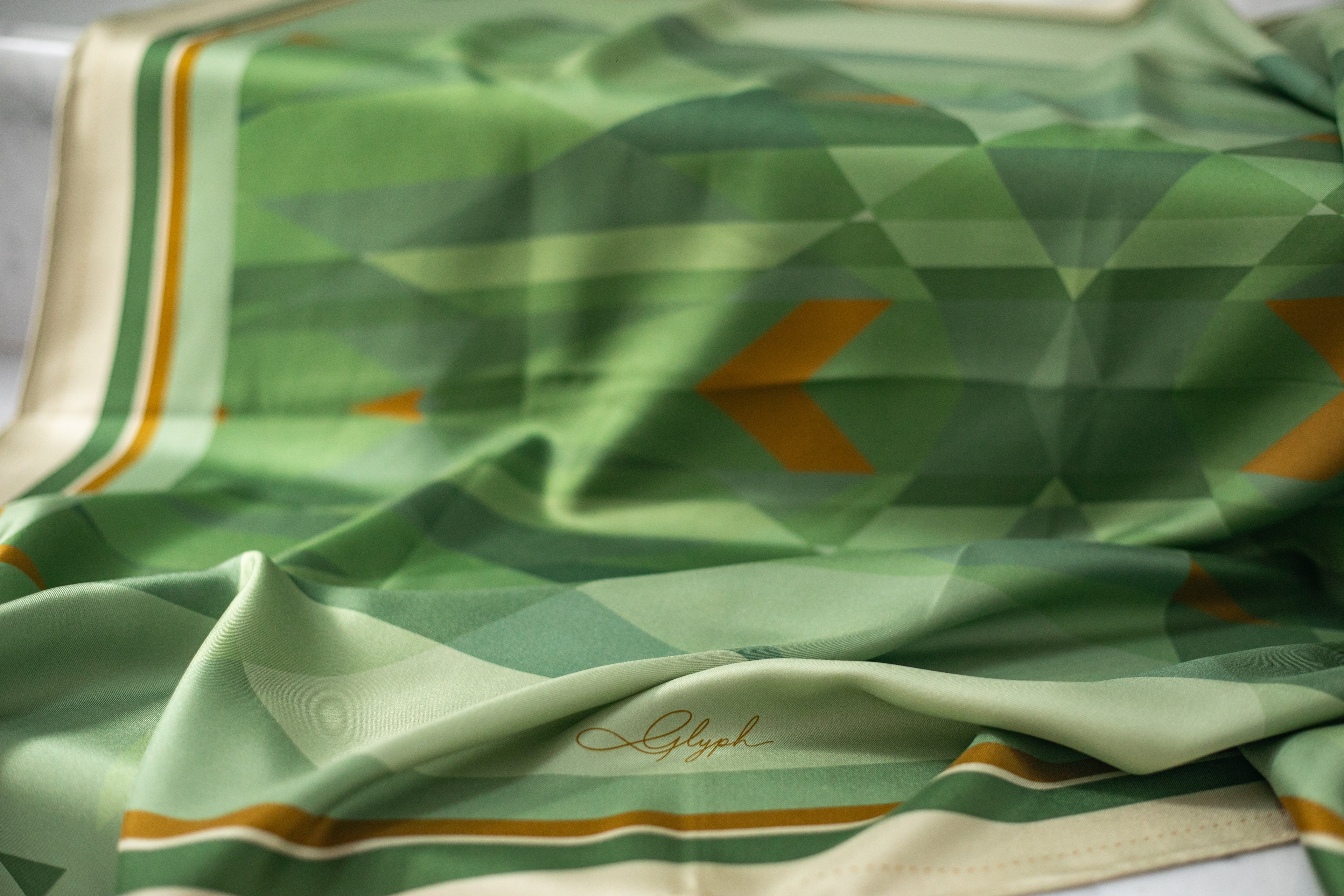 Close-up of the Silent Compass silk scarf by Glyph, showing the silk twill texture, artwork details and Glyph signature.